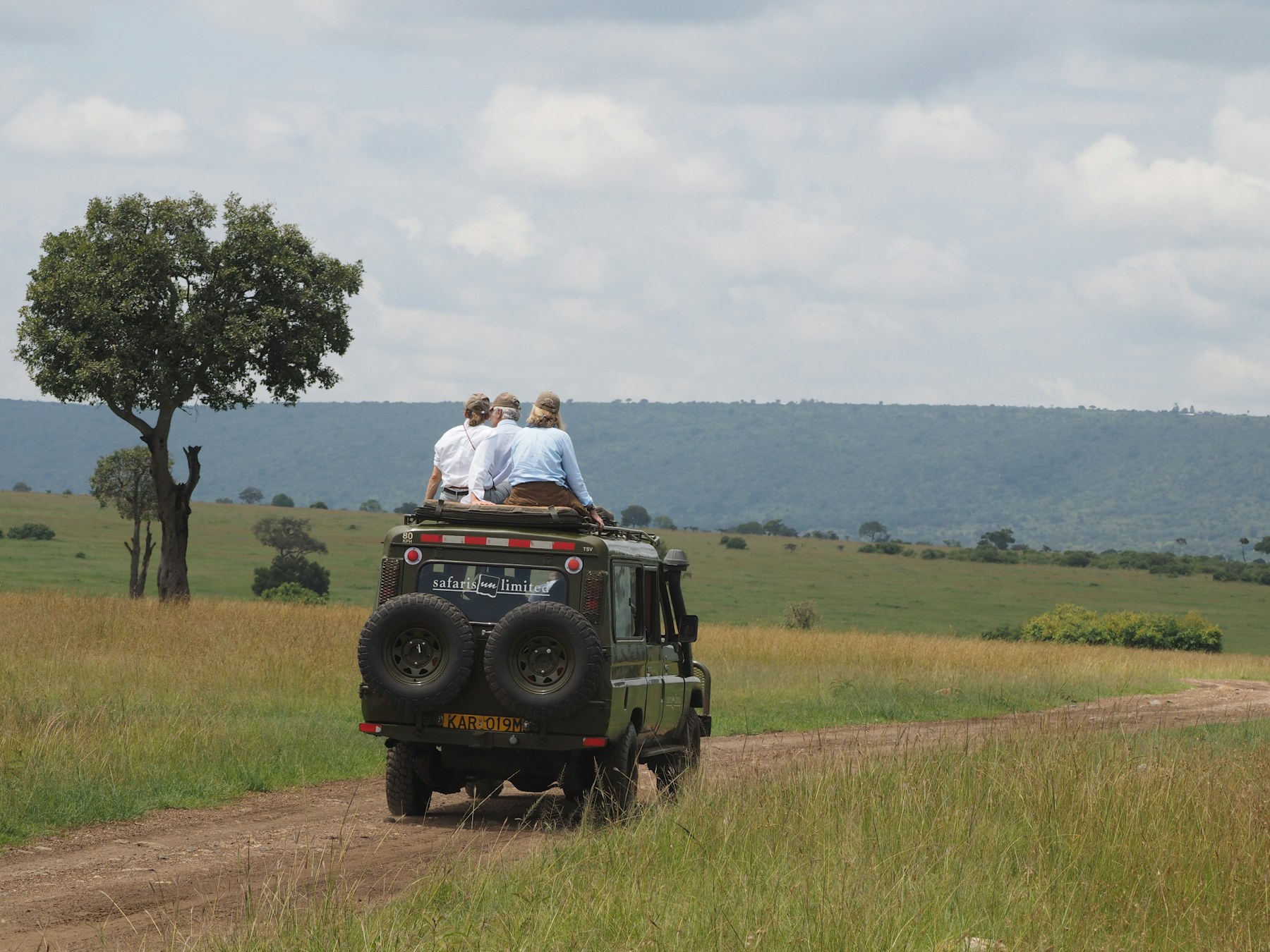 A couple sharing a quiet moment beside a safari vehicle in the Maasai Mara